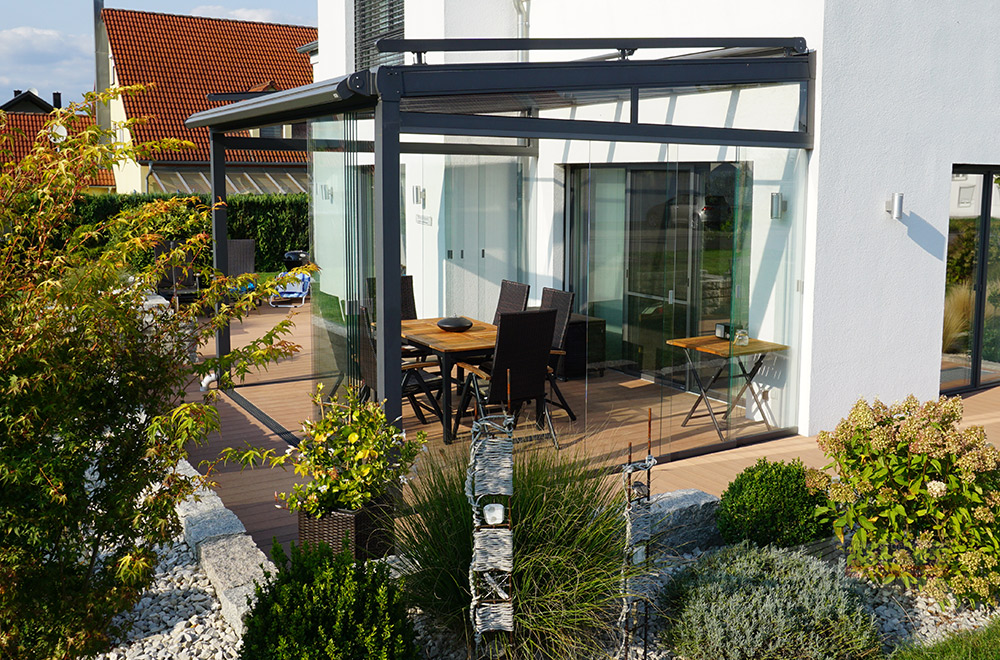 Die Terrasse mit Überdachung und Glasschiebewänden als Gartenzimmer nutzen.